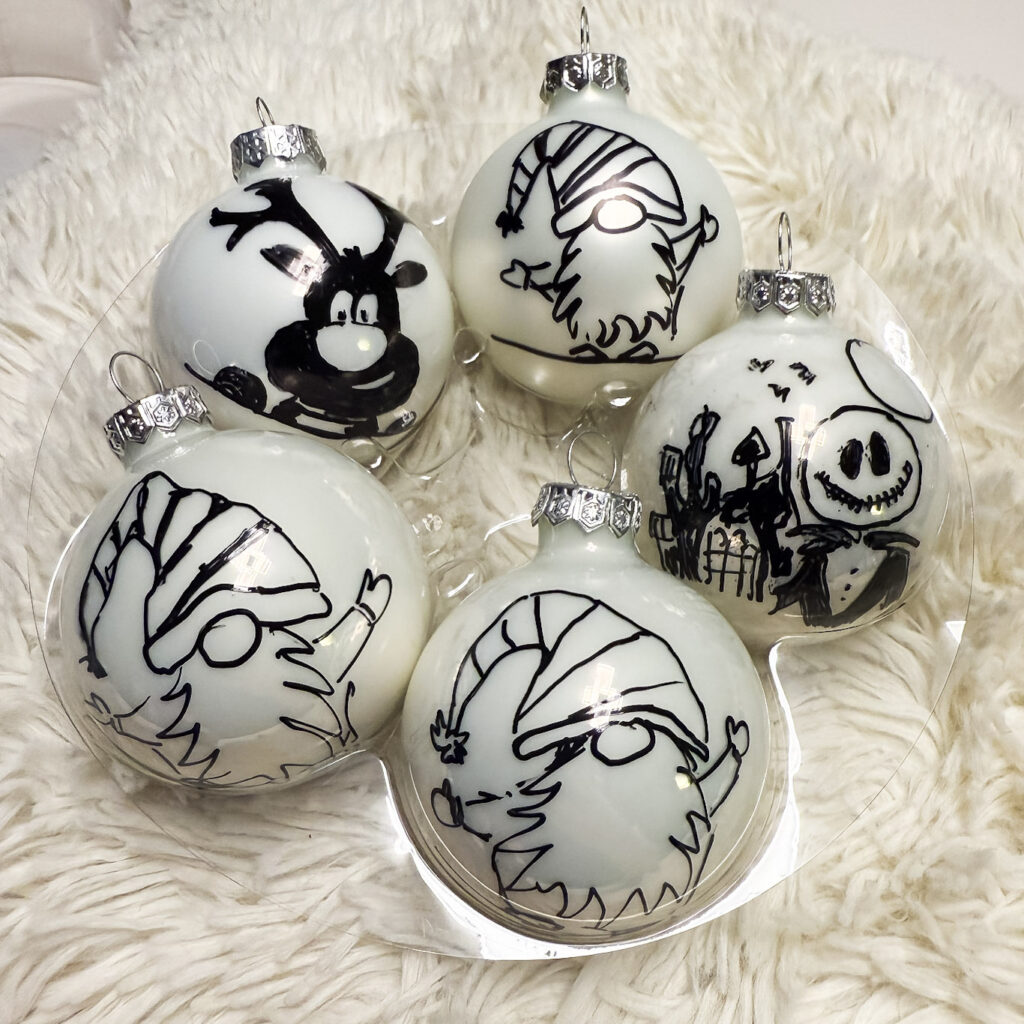 Symboles de Noël sur une boule de Noël en verre, création Atelier VADE.
boule blanche brillante et mate, renne, jack, gnome, nains